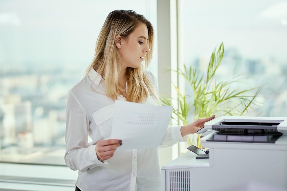 Young Businesswoman Prints on the Printer in the Office